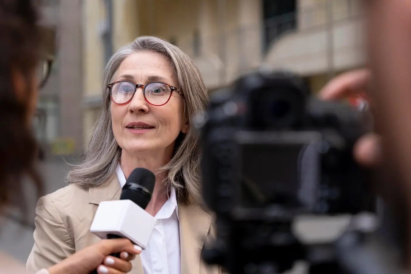 Eine Journalistin führt neben ihrem Kameramann ein Interview.